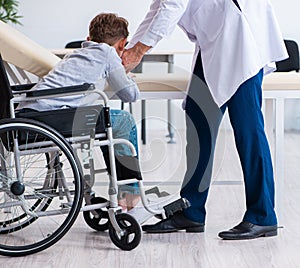 Young male doctor pediatrist and boy in wheel-chair photo