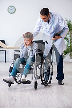 Young male doctor pediatrist and boy in wheel-chair photo