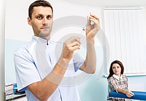 Young male doctor prepares a medicine into the syringe in the office.Doctor holding a syringe