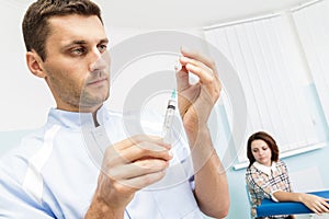 Young male doctor prepares a medicine into the syringe in the office.Doctor holding a syringe