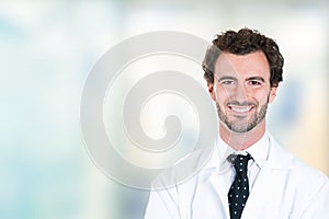 Young male doctor smiling standing in hospital hallway