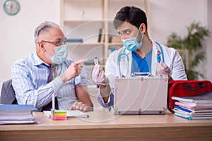 Young male doctor visiting old businessman at workplace