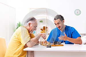 Young male doctor visiting old patient at home