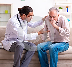 Young male doctor visiting old patient at home