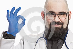 A young male doctor in a white coat holds a transparent capsule in his hand. White background. Close-up