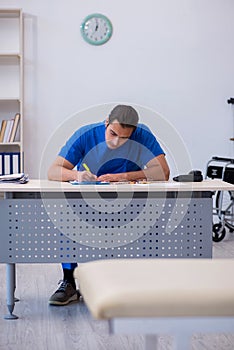 Young male doctor writing prescription in the clinic