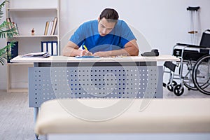 Young male doctor writing prescription in the clinic