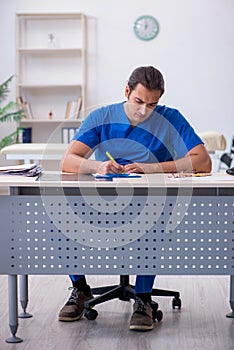 Young male doctor writing prescription in the clinic