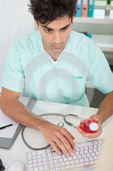 young male doctor writing prescription on computer