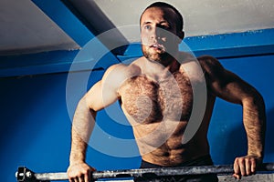 Young male doing pull ups on bar in cross fit training gym