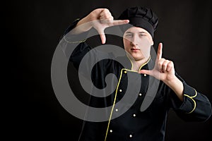 Young male dressed in a black chef suit frameing