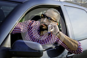 A young male driver talking on a cell phone while driving a car.