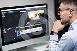 Young male editor editing video on computer at workplace office