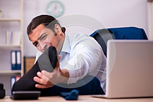 Young male employee doing physical exercises at workplace