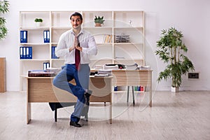 Young male employee doing yoga exercises during break