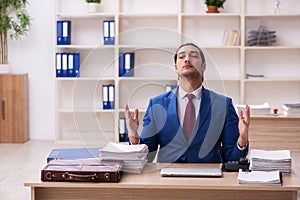 Young male employee doing yoga exercises during break