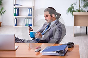 Young male employee drinking coffee in the office