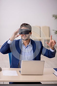 Young male employee enjoying virtual glasses at workplace