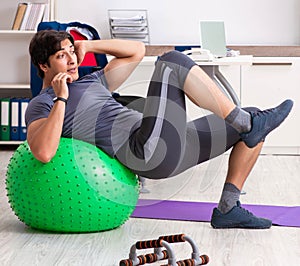 Young male employee exercising in the office