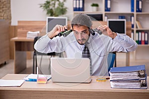 Young male employee holding binoculars in industrial espionage c