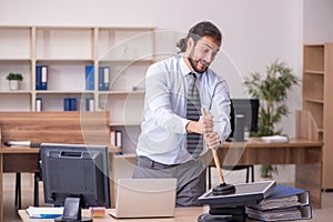 Young male employee holding plunger in funny concept