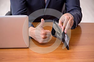 Young male employee holding wallet in remuneration concept