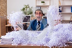 Young male employee and a lot of cut papers in the office