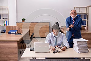 Young male employee and old boss burning papers at workplace