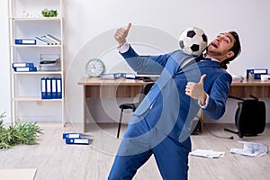 Young male employee playing football in the office