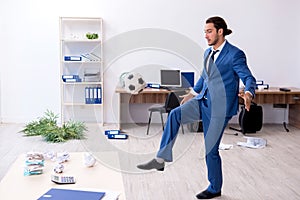 Young male employee playing football in the office