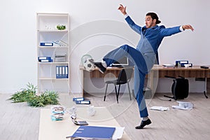 Young male employee playing football in the office