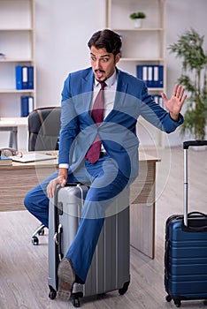 Young male employee preparing for trip at workplace