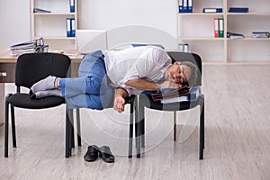 Young male employee sleeping in the office on chairs