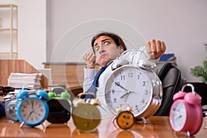 Young male employee sleeping in the office in time management co