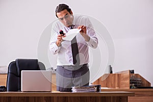 Young male employee stapling paper in the office