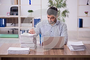 Young male employee and too much work in the office