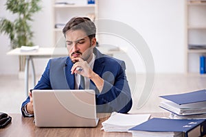 Young male employee unhappy with excessive work in the office