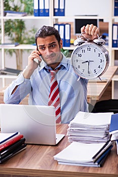 Young male employee unhappy with excessive work in time manageme photo