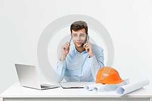 Young male engineer speaking on the phone in his office on grey