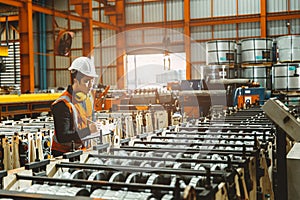 Young male engineer supervisor working QC in metal sheet manufactory work checking production line photo