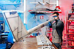 Young male engineer or technician testing simetry of drone details in lab. Aircraft capable of GPS surveillance. Carbon. photo