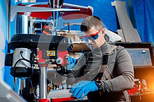 Young male engineer or technician using drill for drone details in lab. Aircraft capable of GPS surveillance. Carbon.