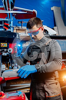 Young male engineer or technician using drill for drone details in lab. Aircraft capable of GPS surveillance. Carbon.