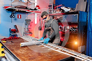 Young male engineer or technician working on drone details in lab. Aircraft capable of GPS surveillance. Carbon.