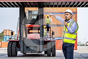 Young male engineer Use of radio communication to control container load in industrial in front of machine lift container