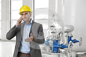 Young male engineer using cell phone in industry