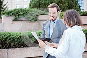 Young male and female business people talking in front of an office building, having a meeting and discussing