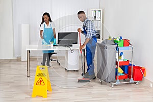 Young Male And Female Cleaners Cleaning Office