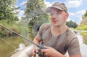 Young male fisherman in a boat with a fishing rod