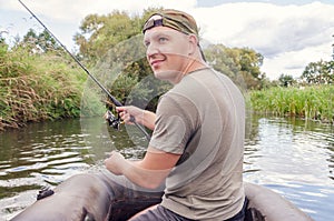 Young male fisherman in a boat with a fishing rod